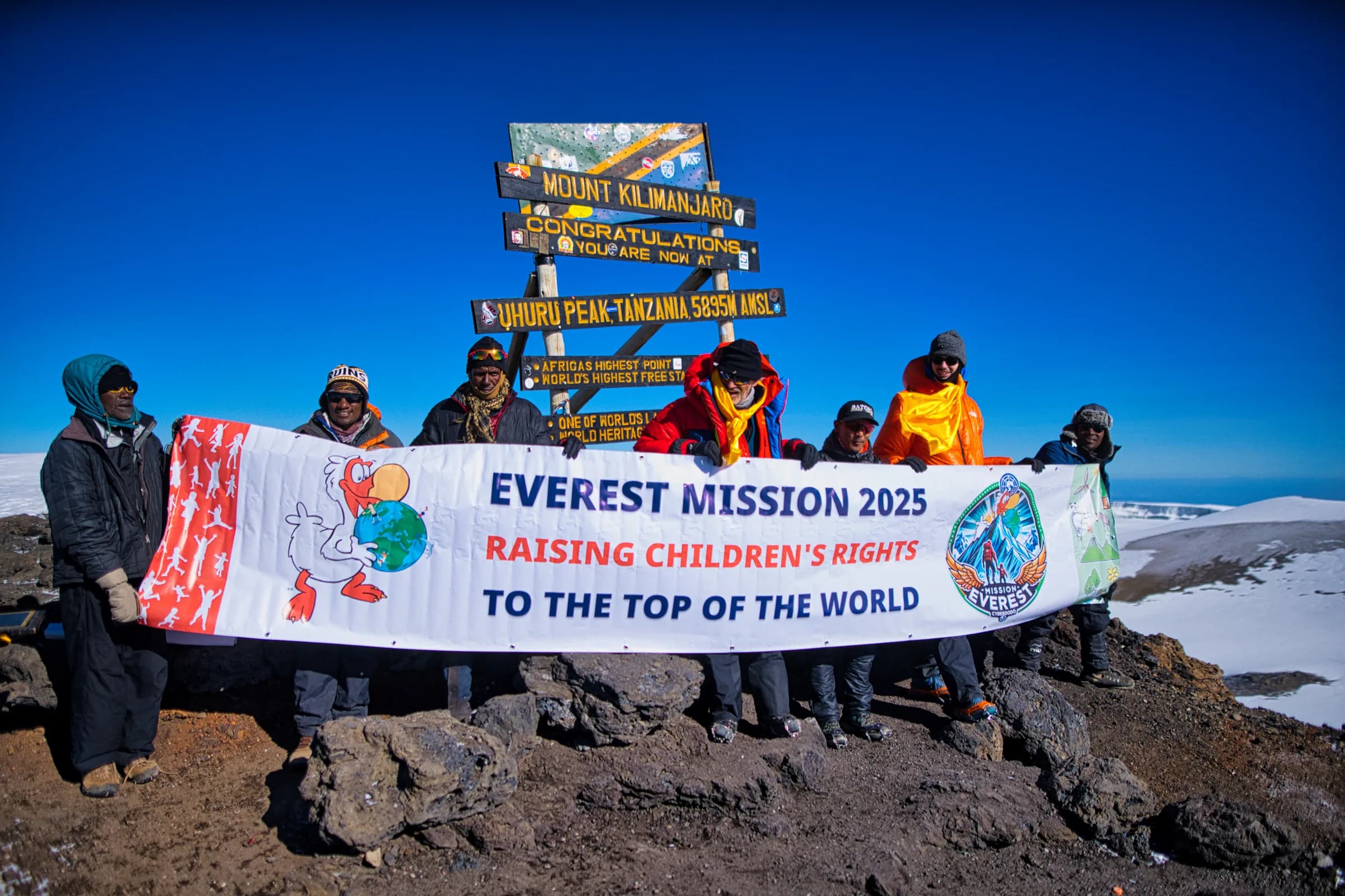 Au sommet du Kilimandjaro, l’équipe tient la bannière « Everest Mission 2025, Raising children’s rights to the top of the world ».